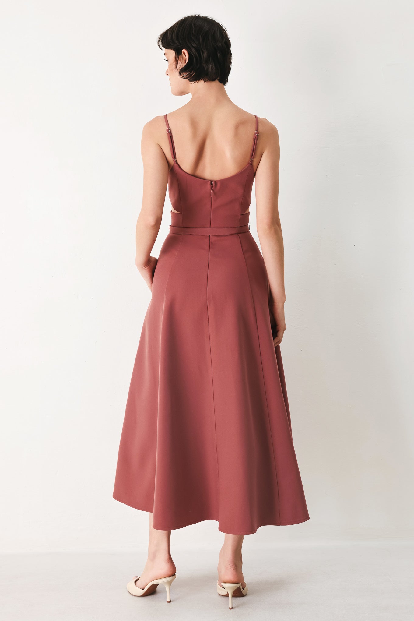 Woman wearing a rose pink midi dress with cut-out design featuring cam top, cut out at waistline, self belt, circle skirt and back zipper closure | FREEMARKET