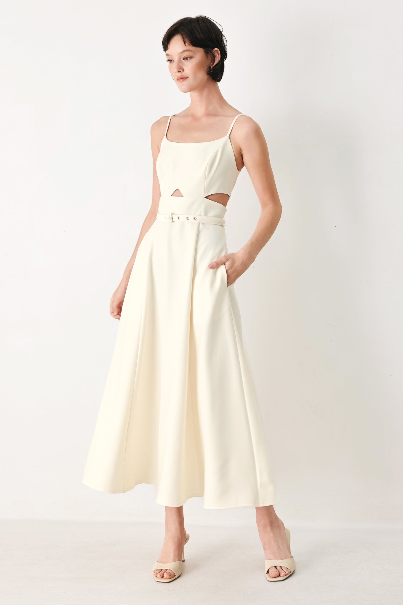 Woman wearing an ivory midi dress with cut-out design featuring cam top, cut out at waistline, self belt, circle skirt and back zipper closure | FREEMARKET