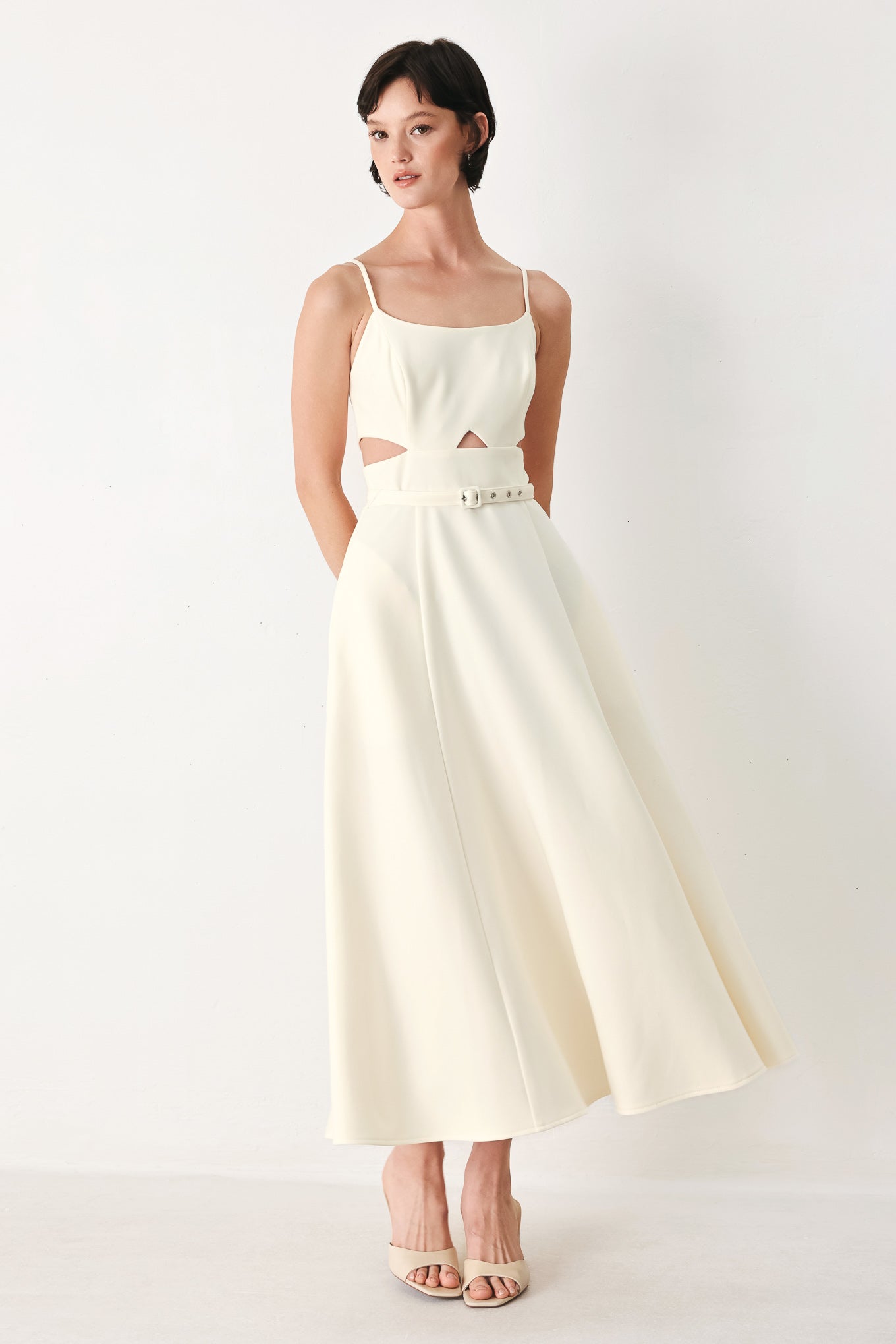 Woman wearing an ivory midi dress with cut-out design featuring cam top, cut out at waistline, self belt, circle skirt and back zipper closure | FREEMARKET