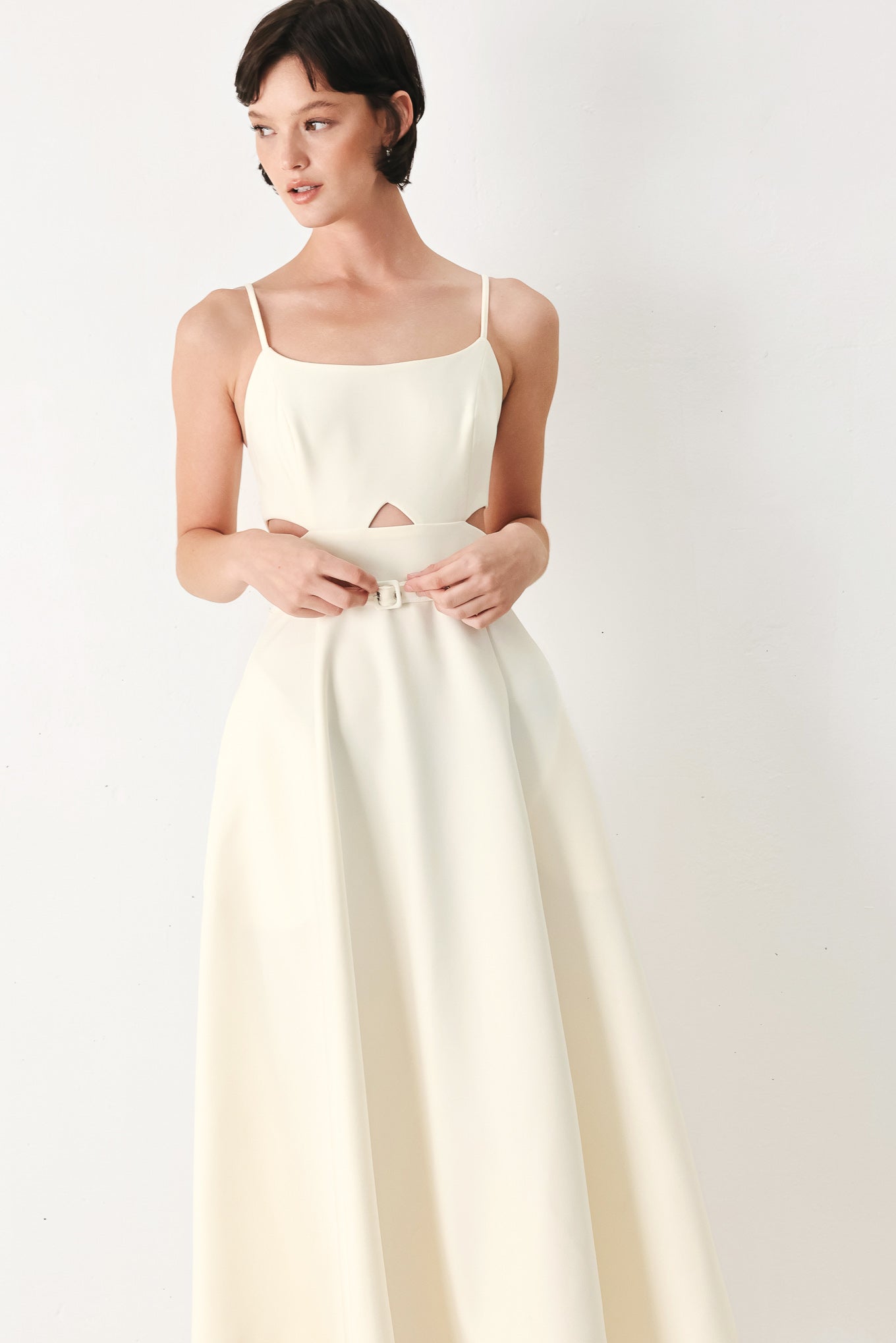 Woman wearing an ivory midi dress with cut-out design featuring cam top, cut out at waistline, self belt, circle skirt and back zipper closure | FREEMARKET