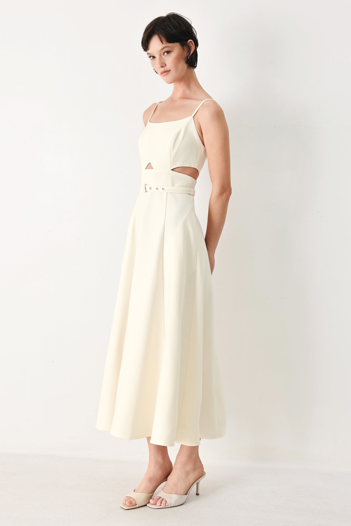 Woman wearing an ivory midi dress with cut-out design featuring cam top, cut out at waistline, self belt, circle skirt and back zipper closure | FREEMARKET