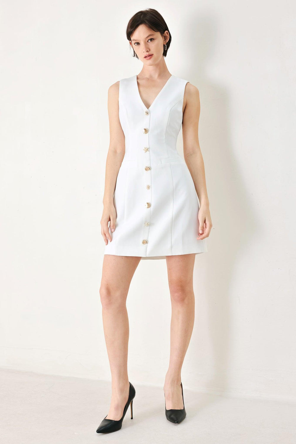 A solid woven mini dress featuring V neckline, sleeveless, button detail and back zipper closure