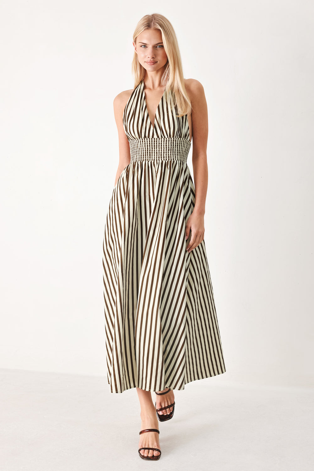 Woman wearing a black and white striped woven midi dress featuring halter neckline with back neck tie, full skirt, pockets and bare back with smocked back waist band | FREEMARKET