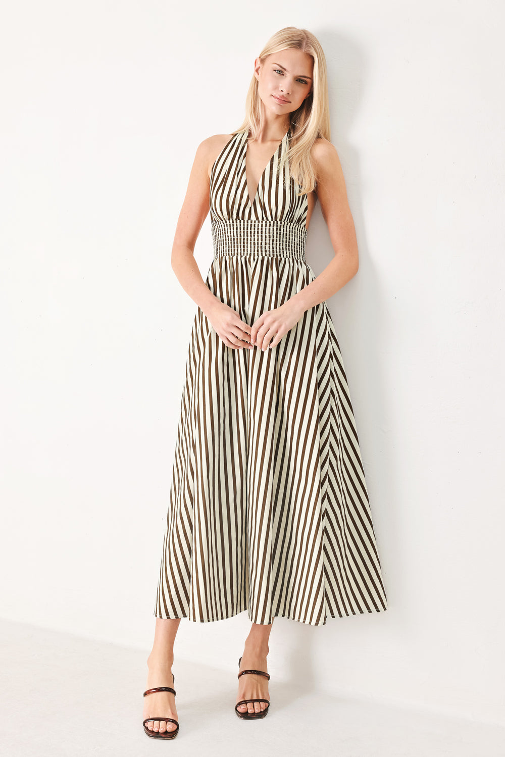 Woman wearing a black and white striped woven midi dress featuring halter neckline with back neck tie, full skirt, pockets and bare back with smocked back waist band | FREEMARKET
