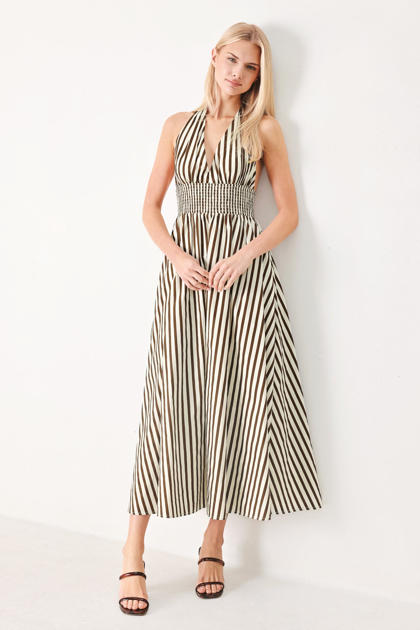Woman wearing a black and white striped woven midi dress featuring halter neckline with back neck tie, full skirt, pockets and bare back with smocked back waist band | FREEMARKET