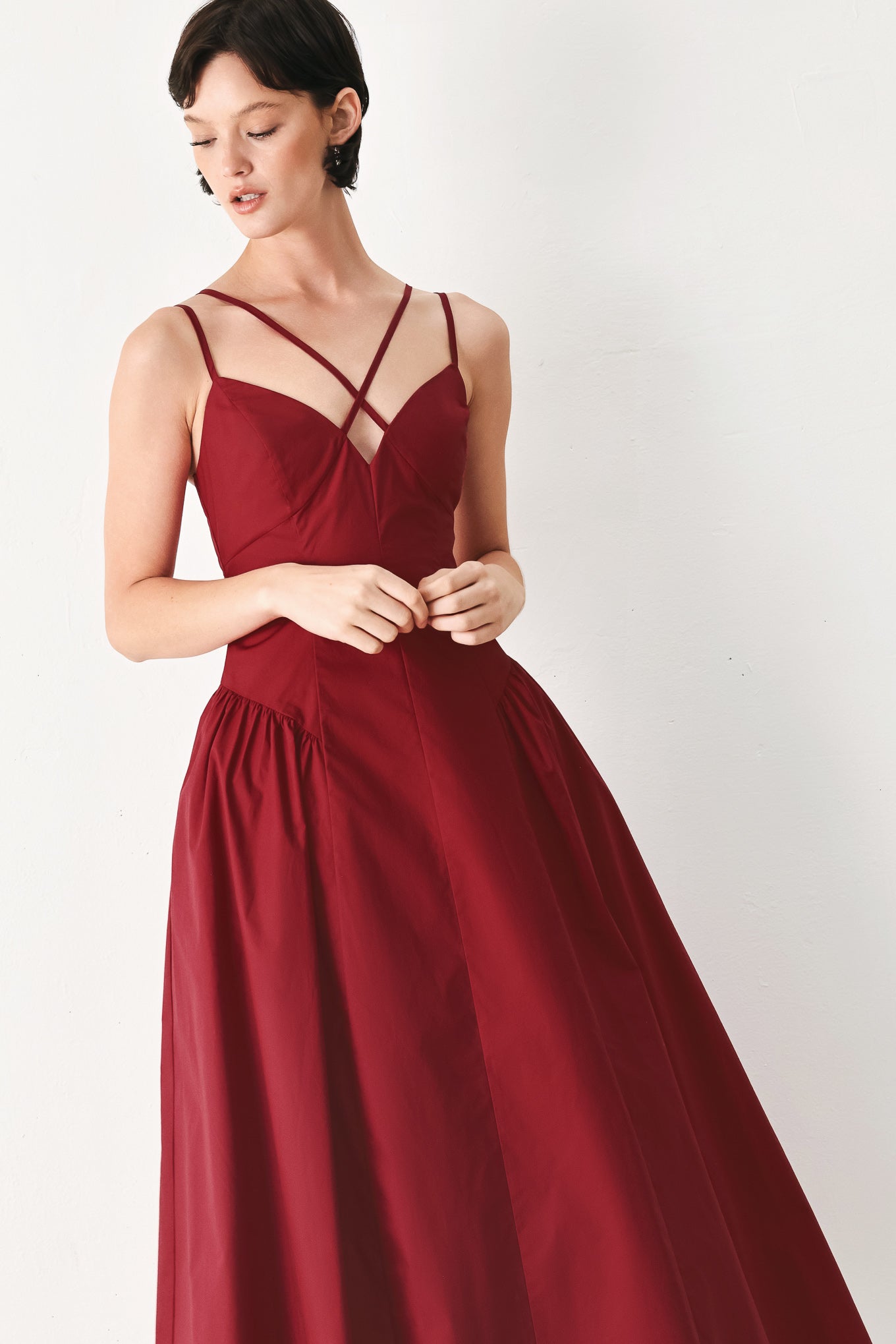 Woman wearing a deep red midi dress featuring cami top with double strap, side shirred skirt and back zipper closure | FREEMARKET