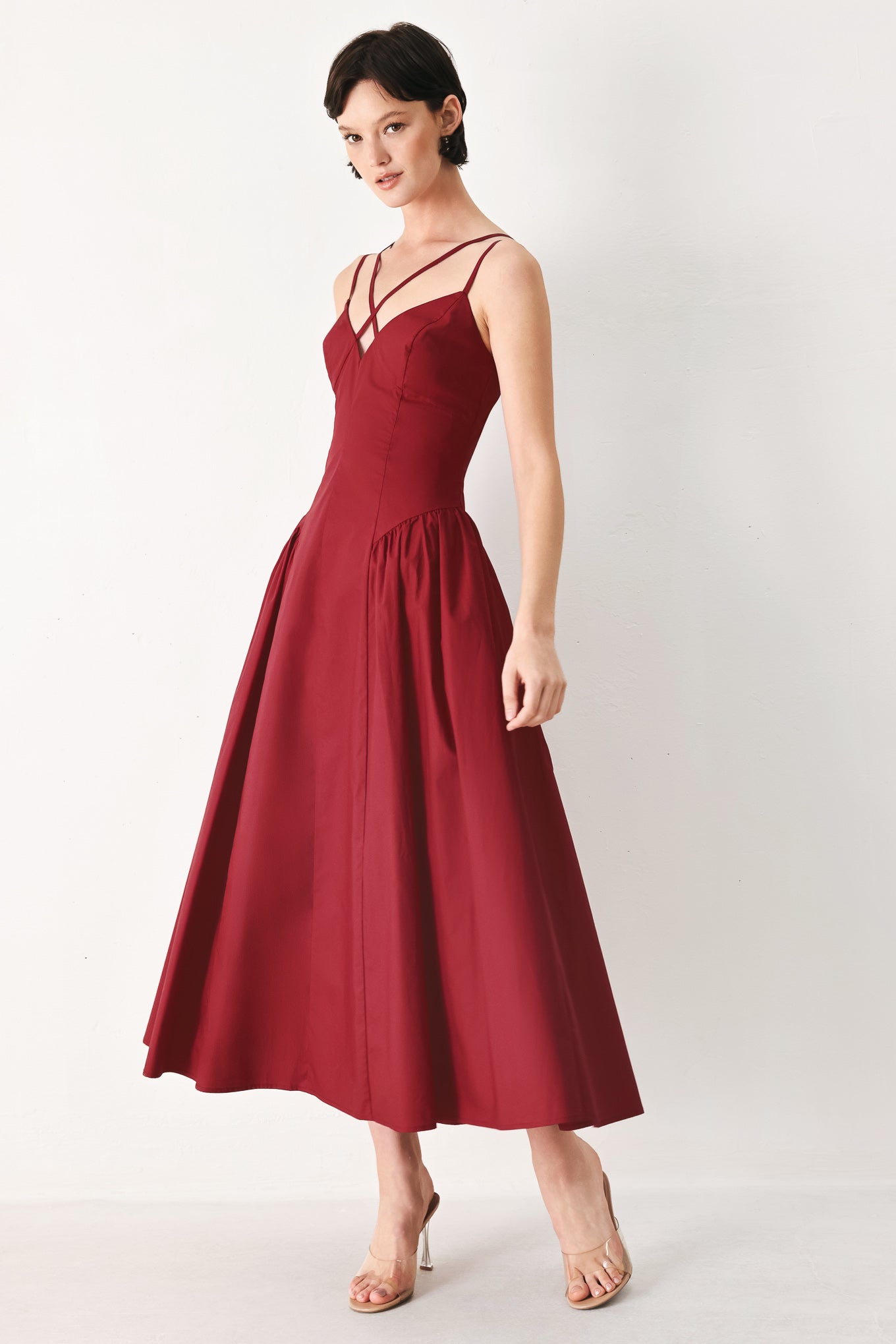 Woman wearing a deep red midi dress featuring cami top with double strap, side shirred skirt and back zipper closure | FREEMARKET