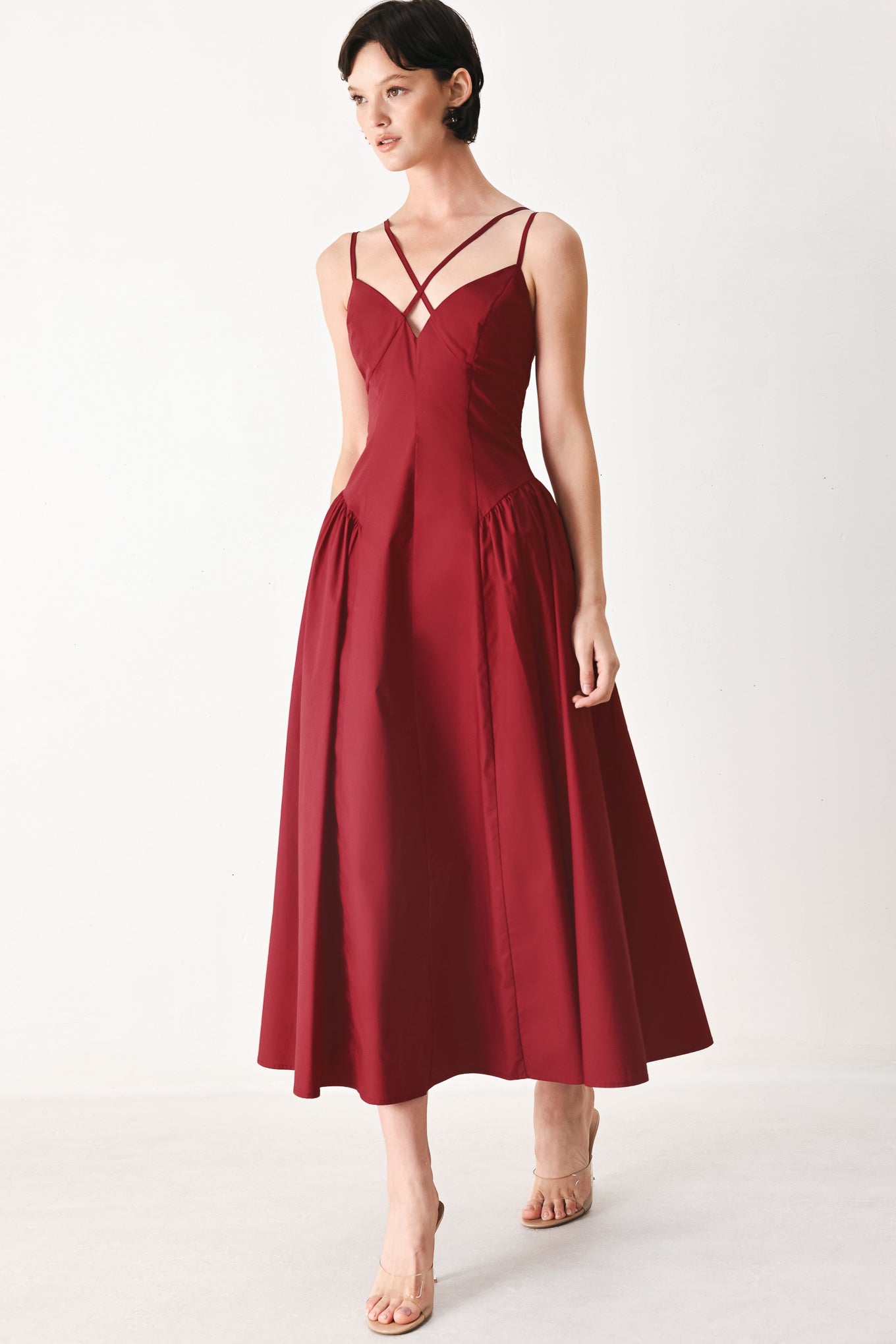Woman wearing a deep red midi dress featuring cami top with double strap, side shirred skirt and back zipper closure | FREEMARKET