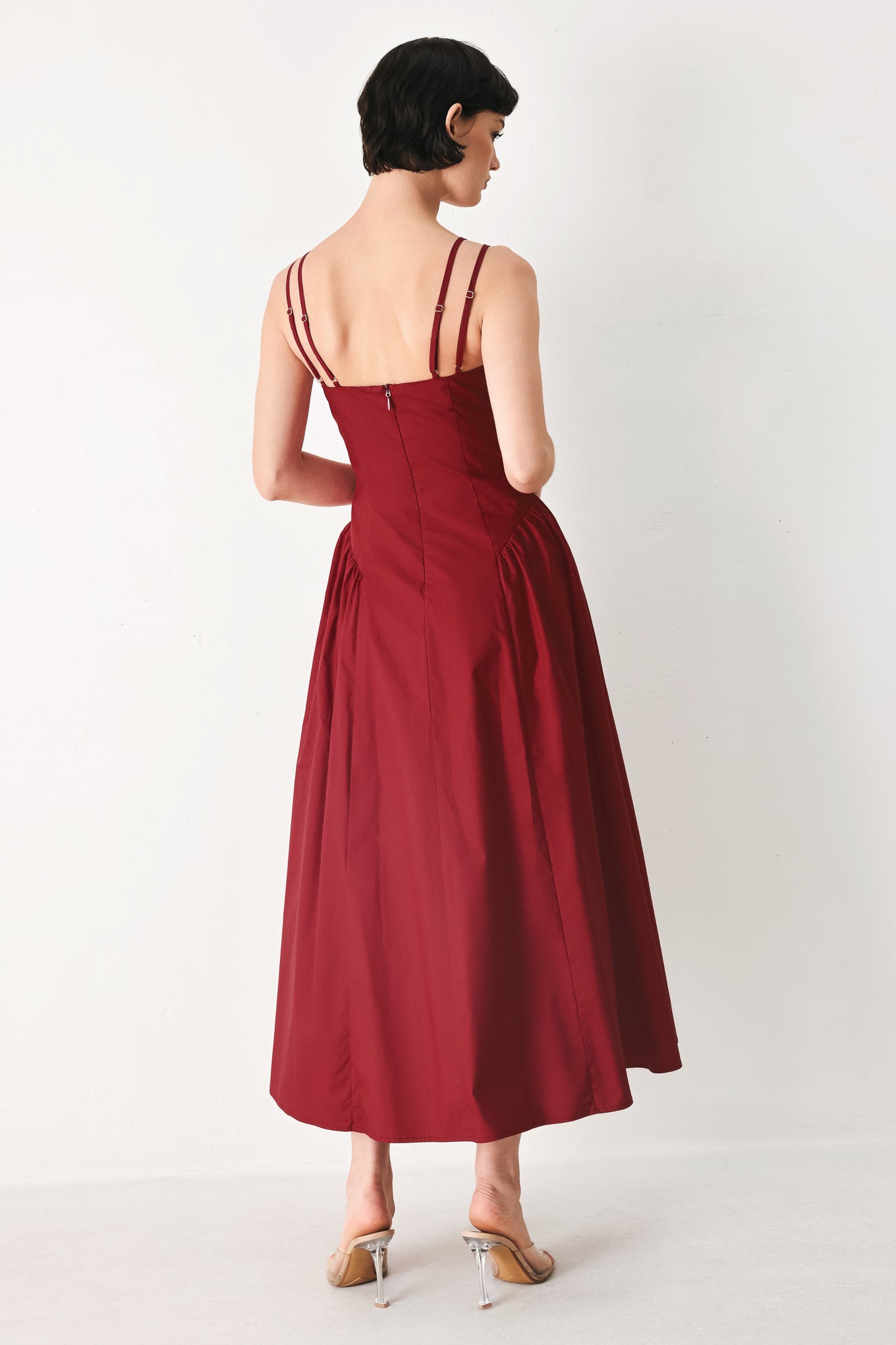 Woman wearing a deep red midi dress featuring cami top with double strap, side shirred skirt and back zipper closure | FREEMARKET
