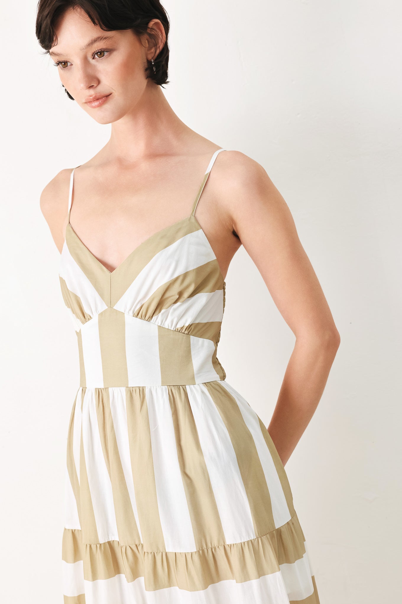 Woman wearing a taupe and white striped maxi dress featuring cami top, waist yoke, tier skirt and smocked back bodice | FREEMARKET