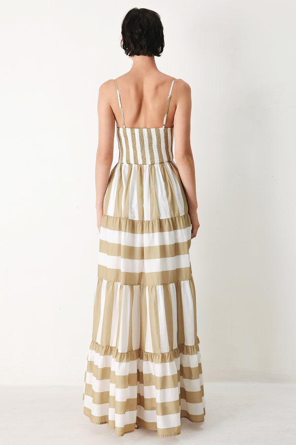Woman wearing a taupe and white striped maxi dress featuring cami top, waist yoke, tier skirt and smocked back bodice | FREEMARKET