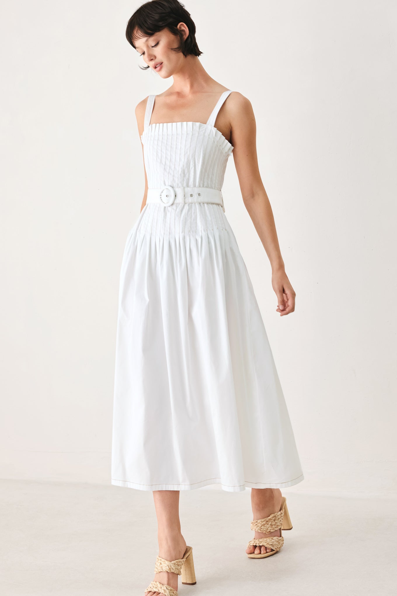 Woman wearing a white midi dress featuring straight neckline, straps, pintuck bodice, self belt and side zipper closure | FREEMARKET