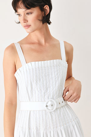 Woman wearing a white midi dress featuring straight neckline, straps, pintuck bodice, self belt and side zipper closure | FREEMARKET