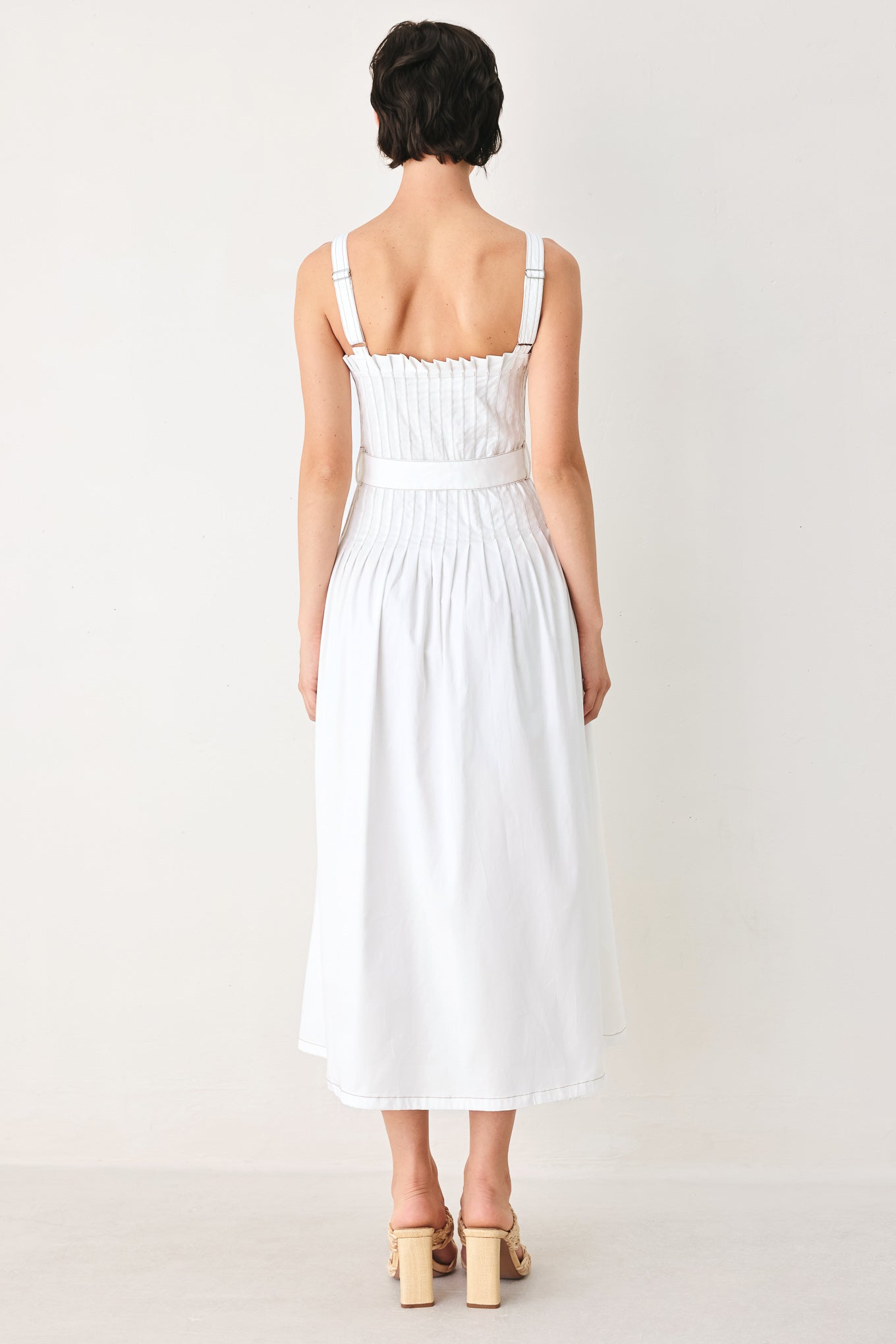 Woman wearing a white midi dress featuring straight neckline, straps, pintuck bodice, self belt and side zipper closure | FREEMARKET