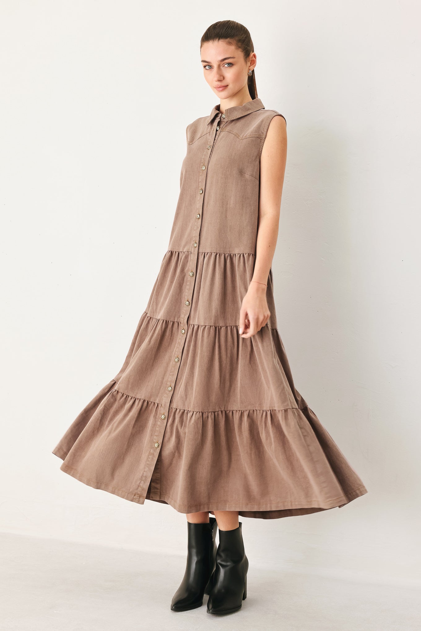 Woman wearing a brown tiered dress with black boots on a white background