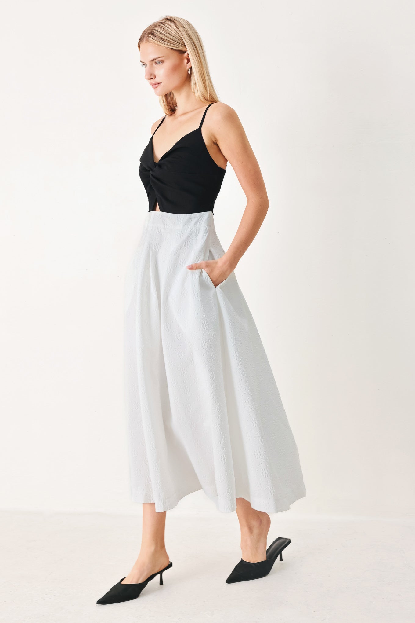 Woman wearing a black top and white midi dress featuring knit top with front twist and cut out, textured full skirt with pockets and back zipper closure | FREEMARKET