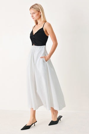Woman wearing a black top and white midi dress featuring knit top with front twist and cut out, textured full skirt with pockets and back zipper closure | FREEMARKET