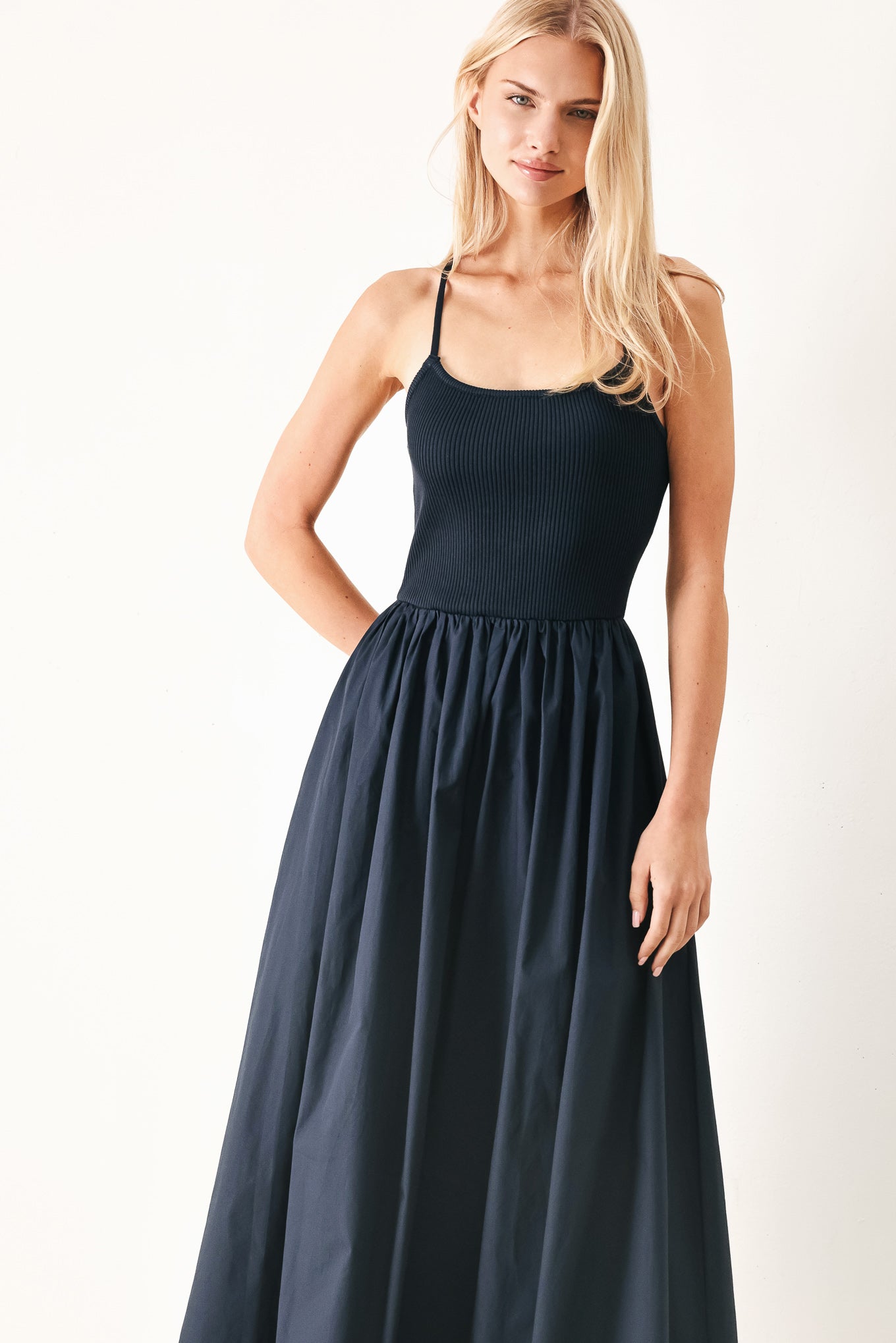 Woman wearing a navy sleeveless  midi dress featuring ribbed sweater knit tank top, solid woven skirt, bare back with lace up tie detail | FREEMARKET