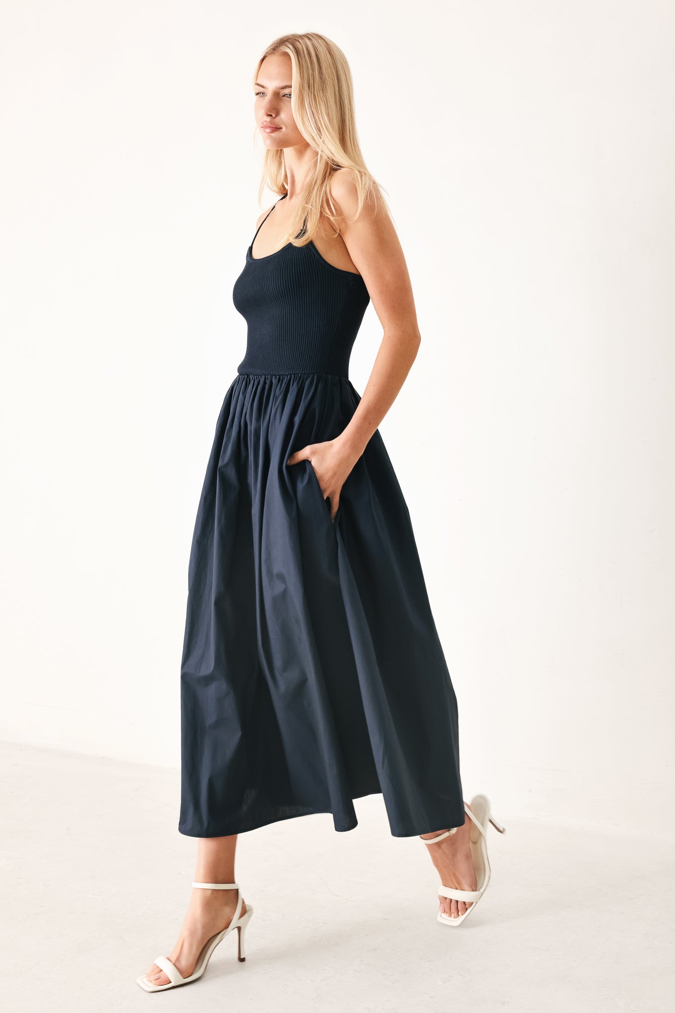 Woman wearing a navy sleeveless  midi dress featuring ribbed sweater knit tank top, solid woven skirt, bare back with lace up tie detail | FREEMARKET