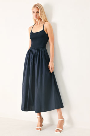 Woman wearing a navy sleeveless  midi dress featuring ribbed sweater knit tank top, solid woven skirt, bare back with lace up tie detail | FREEMARKET