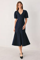 A woman wearing a dark navy blue denim midi dress with short puff sleeves, a V-neckline, and a flared skirt | FREEMARKET