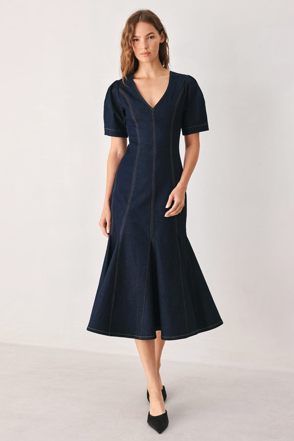A woman wearing a dark navy blue denim midi dress with short puff sleeves, a V-neckline, and a flared skirt | FREEMARKET