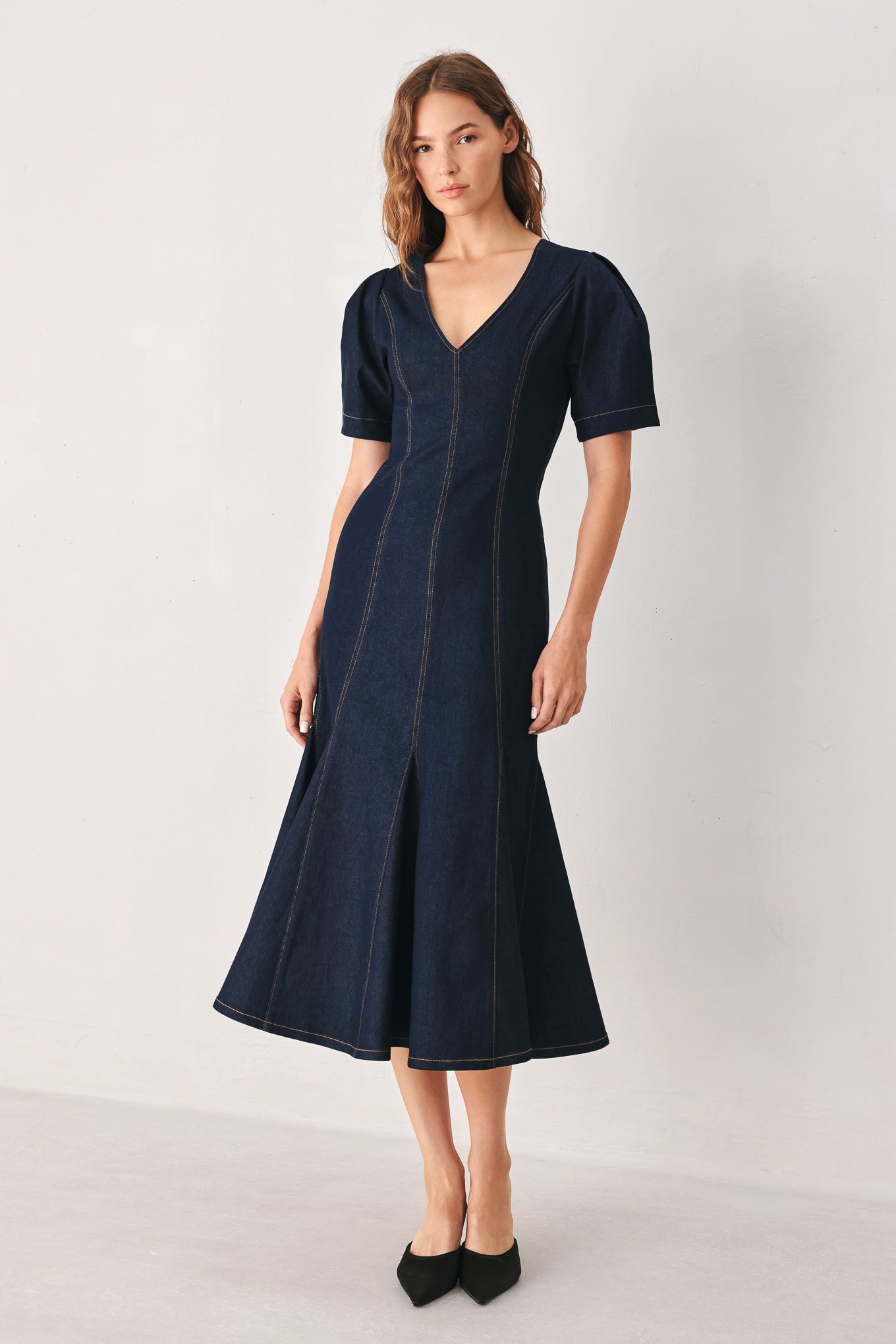 A woman wearing a dark navy blue denim midi dress with short puff sleeves, a V-neckline, and a flared skirt | FREEMARKET