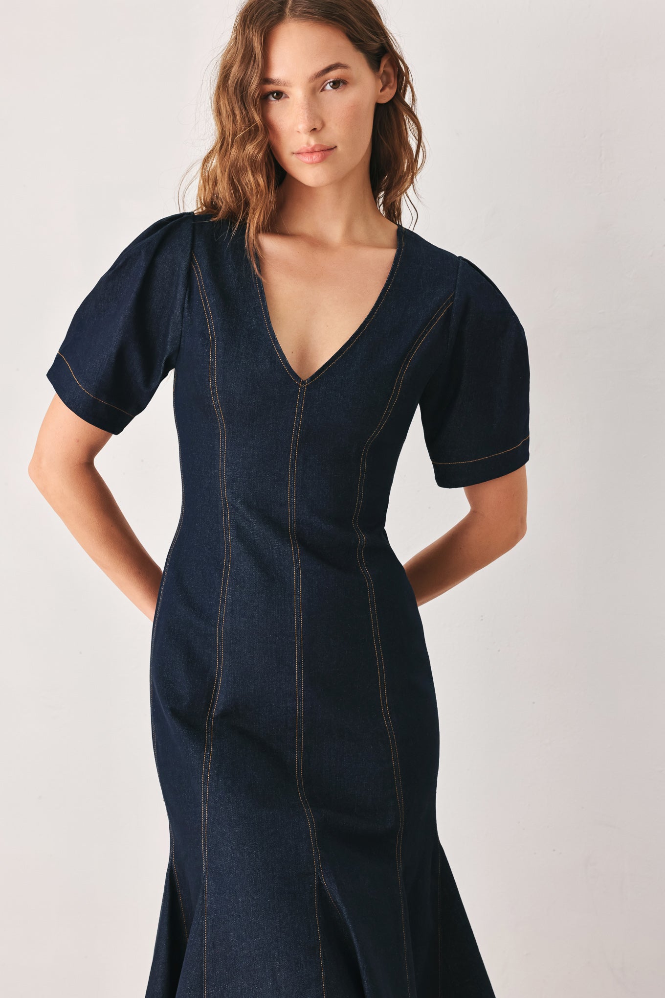 A woman wearing a dark navy blue denim midi dress with short puff sleeves, a V-neckline, and a flared skirt | FREEMARKET