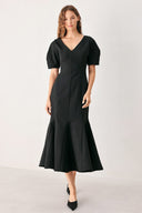 A woman wearing a black midi dress with short puff sleeves, a V-neckline, and a flared hem | FREEMARKET