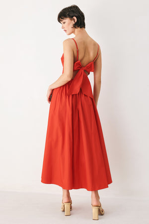 Woman wearing a red midi dress featuring straight neckline, straps, waist cutout, full skirt, and tie detail | FREEMARKET