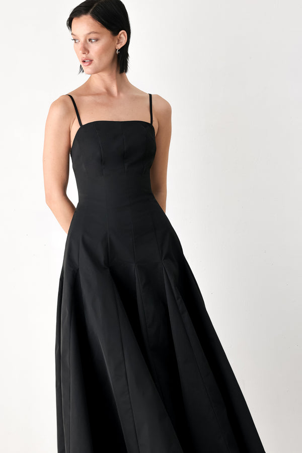 A woman modeling a black midi dress with thin spaghetti straps, a structured square neckline, and a flared skirt | FREEMARKET