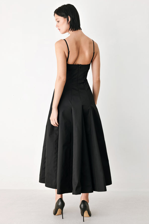 A woman modeling a black midi dress with thin spaghetti straps, a structured square neckline, and a flared skirt | FREEMARKET