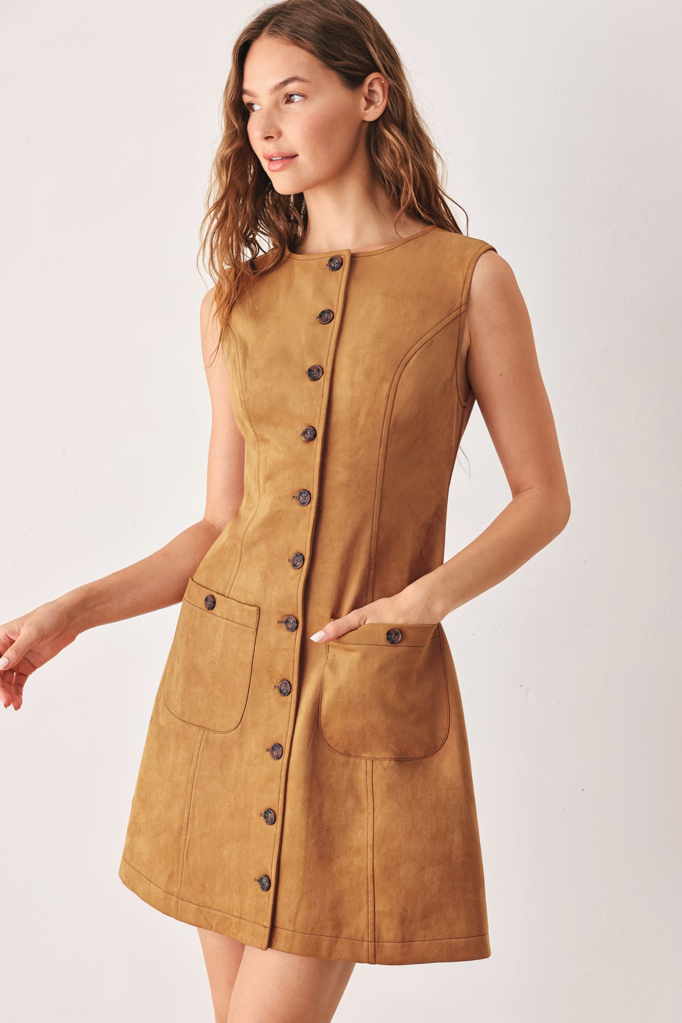 A woman wearing a sleeveless caramel dress with a front button placket and two front patch pockets | FREEMARKET