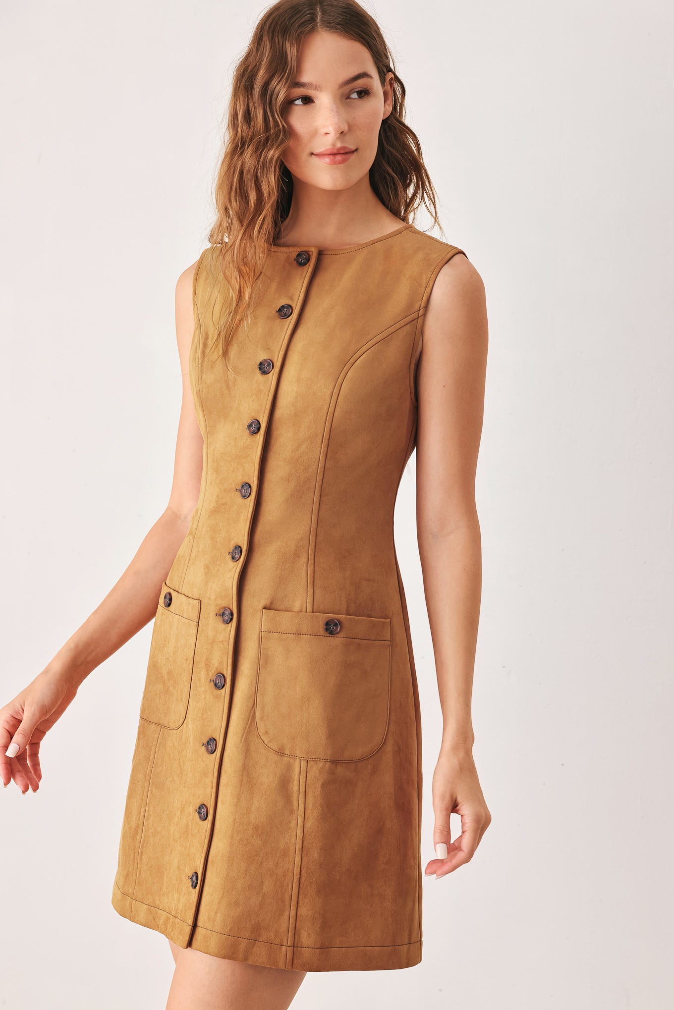 A woman wearing a sleeveless caramel dress with a front button placket and two front patch pockets | FREEMARKET