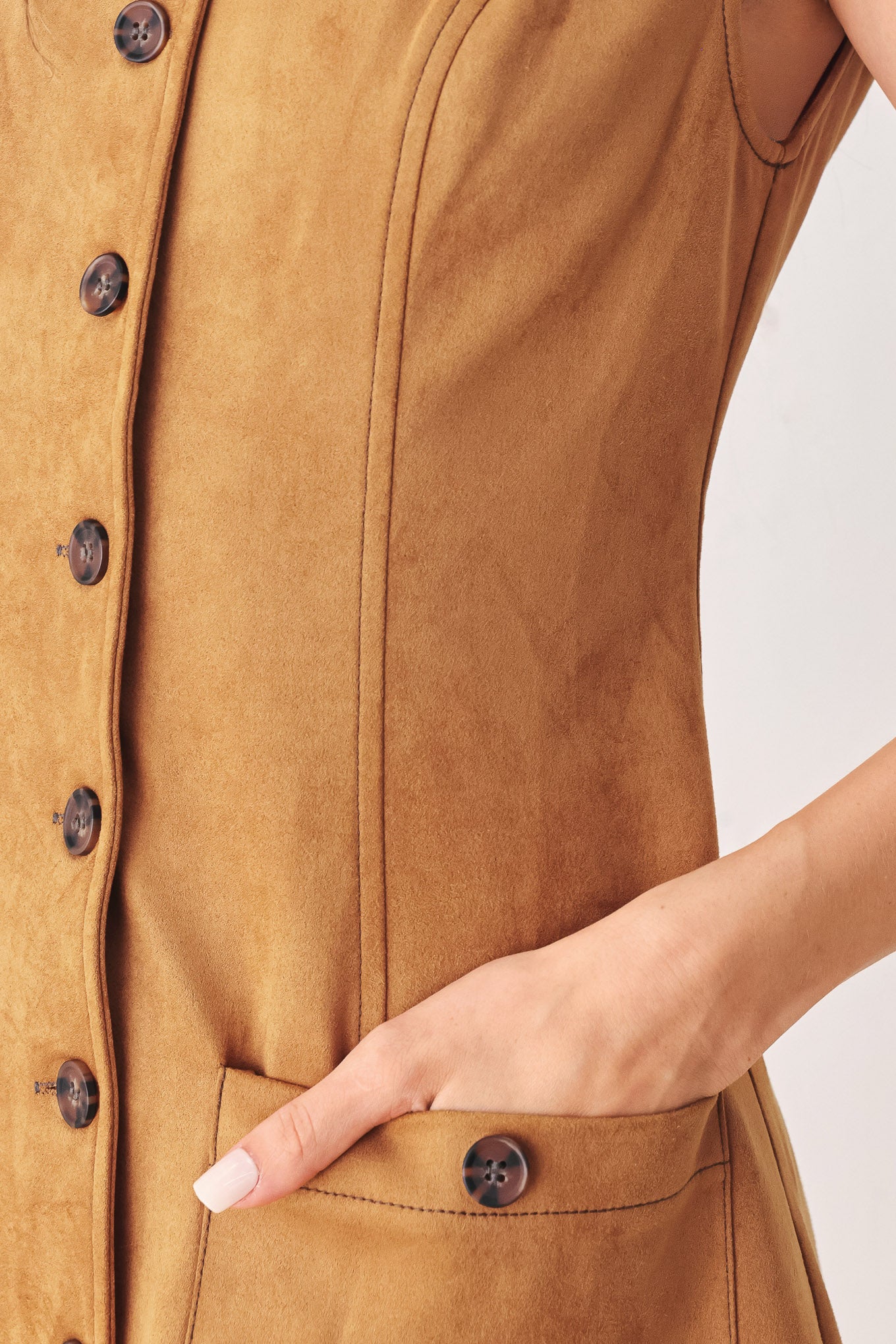 A woman wearing a sleeveless caramel dress with a front button placket and two front patch pockets | FREEMARKET