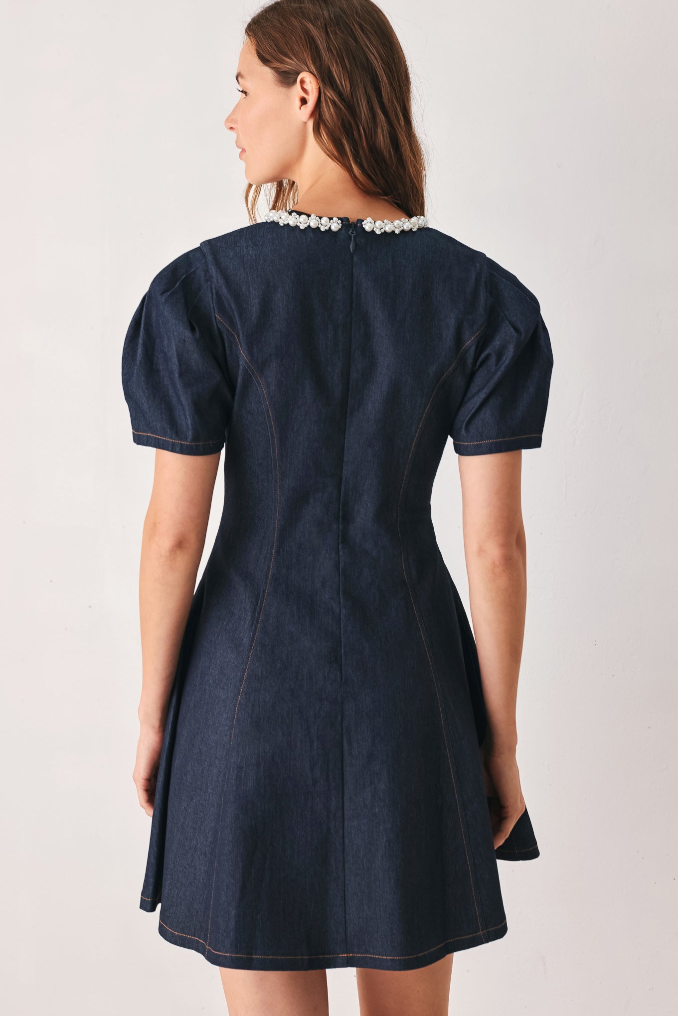 A woman wearing a dark navy blue mini dress with short puff sleeves, a round neckline accented with a white pearl collar, and a flared skirt | FREEMARKET