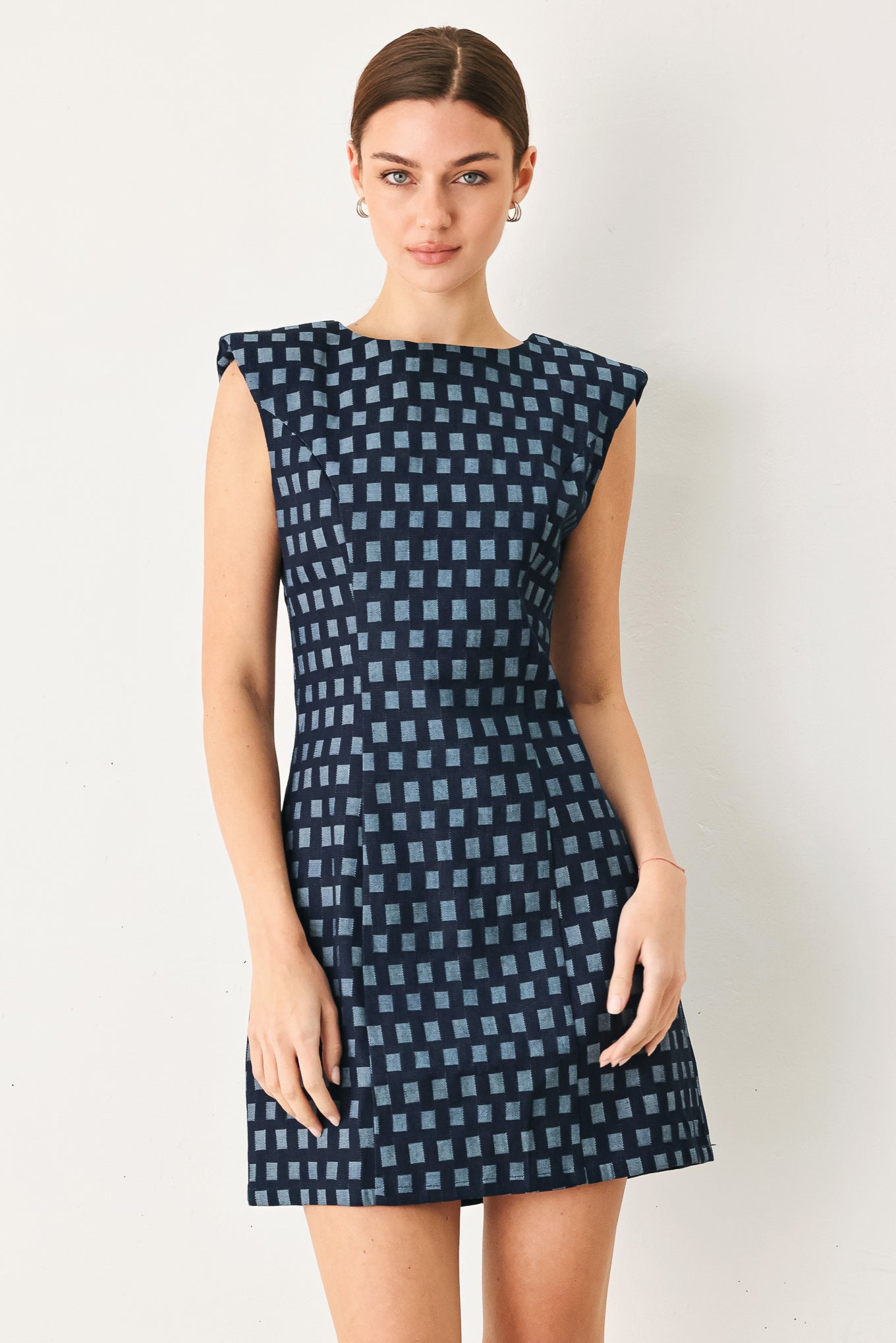 Woman wearing a blue checkered dress against a white background