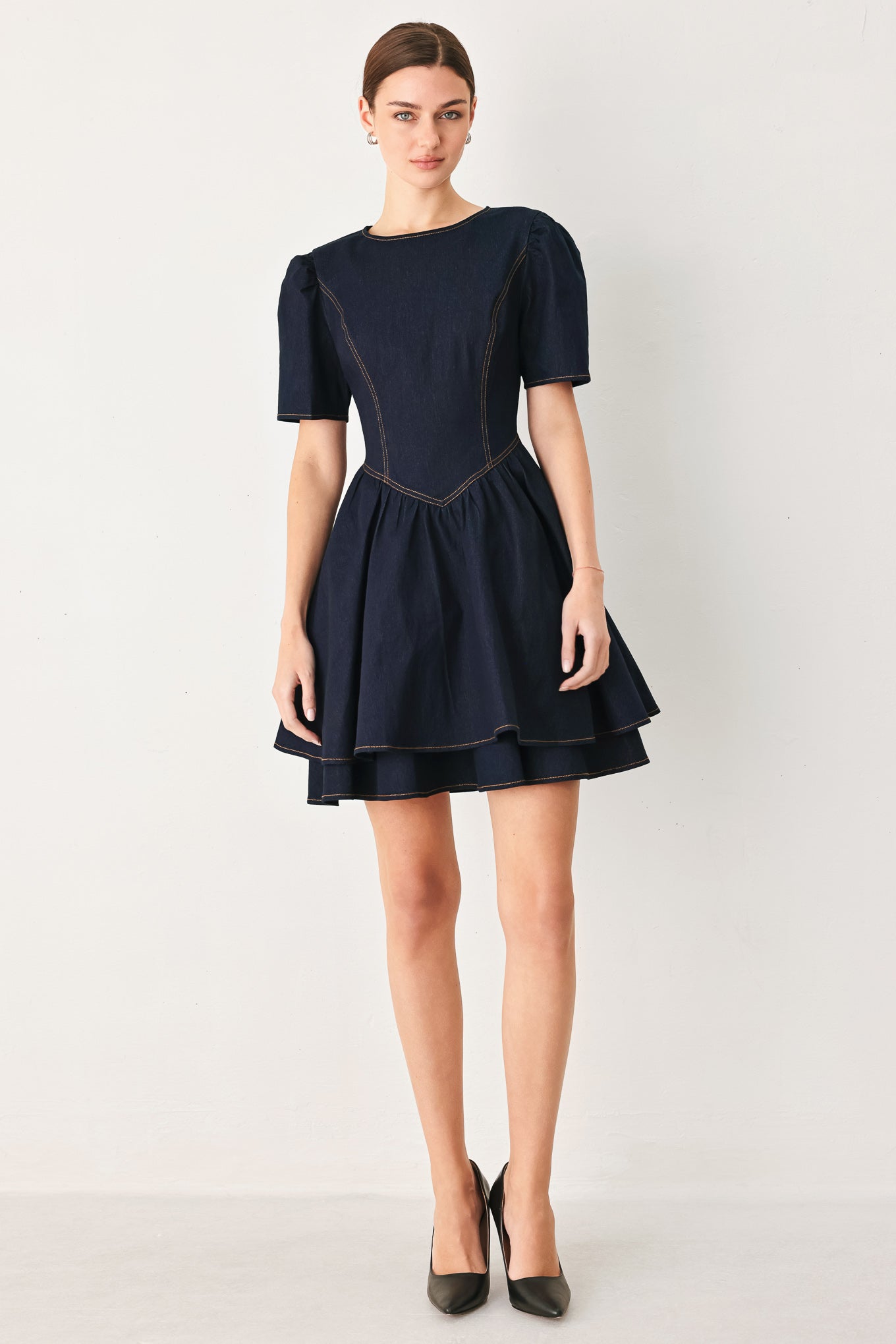 Woman wearing a dark denim navy blue mini dress featuring round neckline, short puff sleeve, basque waist, double layer skirt and back zipper closure | FREEMARKET
