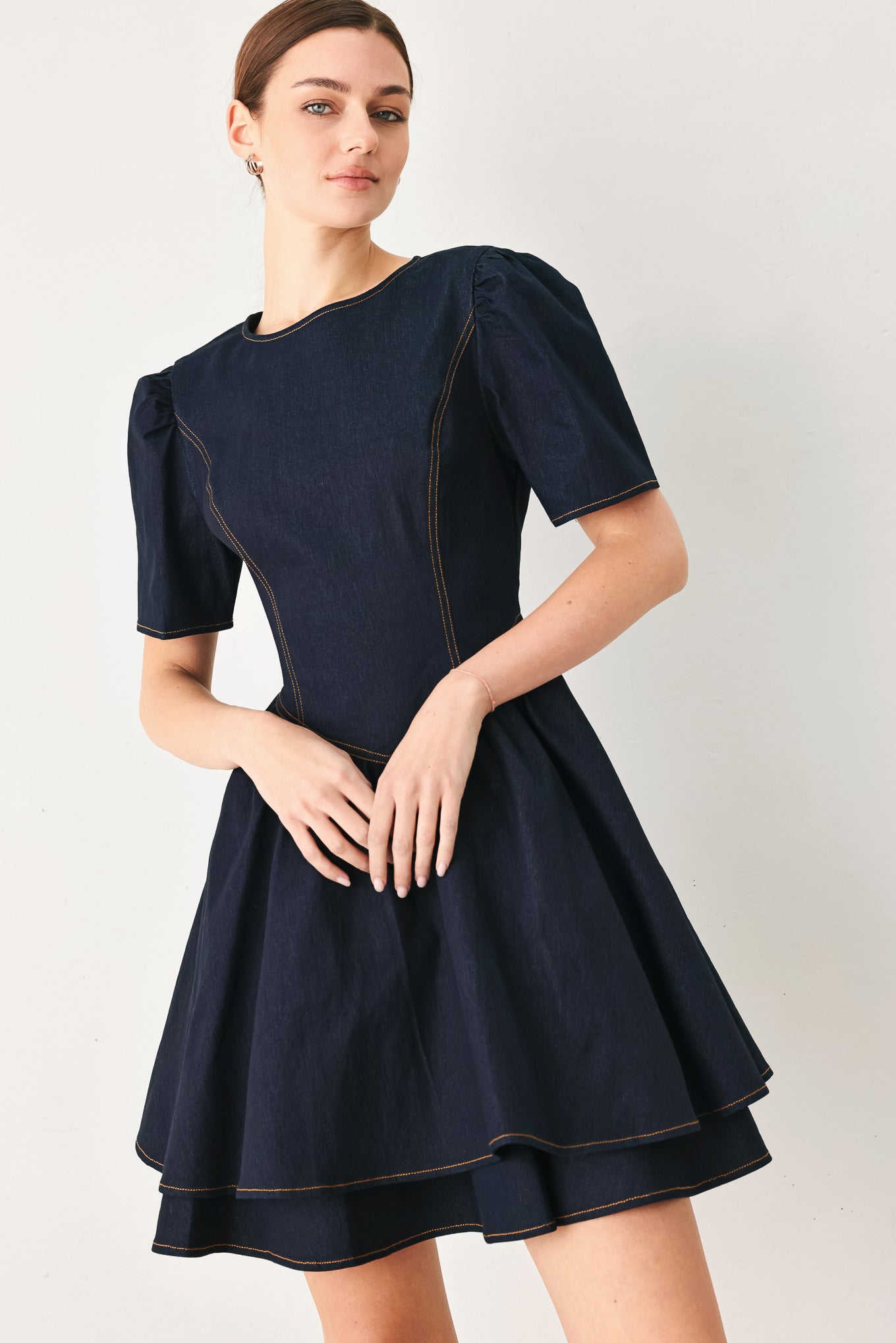 Woman wearing a dark denim navy blue mini dress featuring round neckline, short puff sleeve, basque waist, double layer skirt and back zipper closure | FREEMARKET