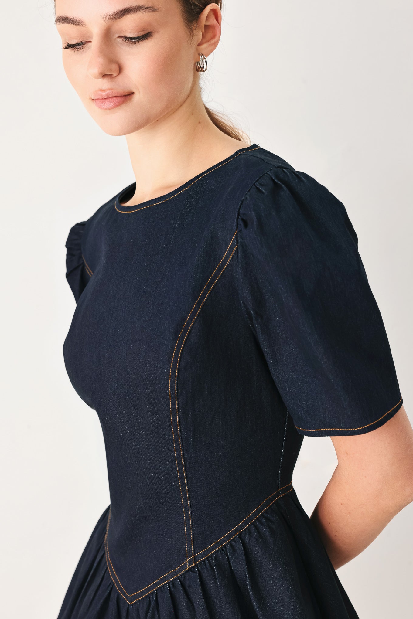 Woman wearing a dark denim navy blue mini dress featuring round neckline, short puff sleeve, basque waist, double layer skirt and back zipper closure | FREEMARKET