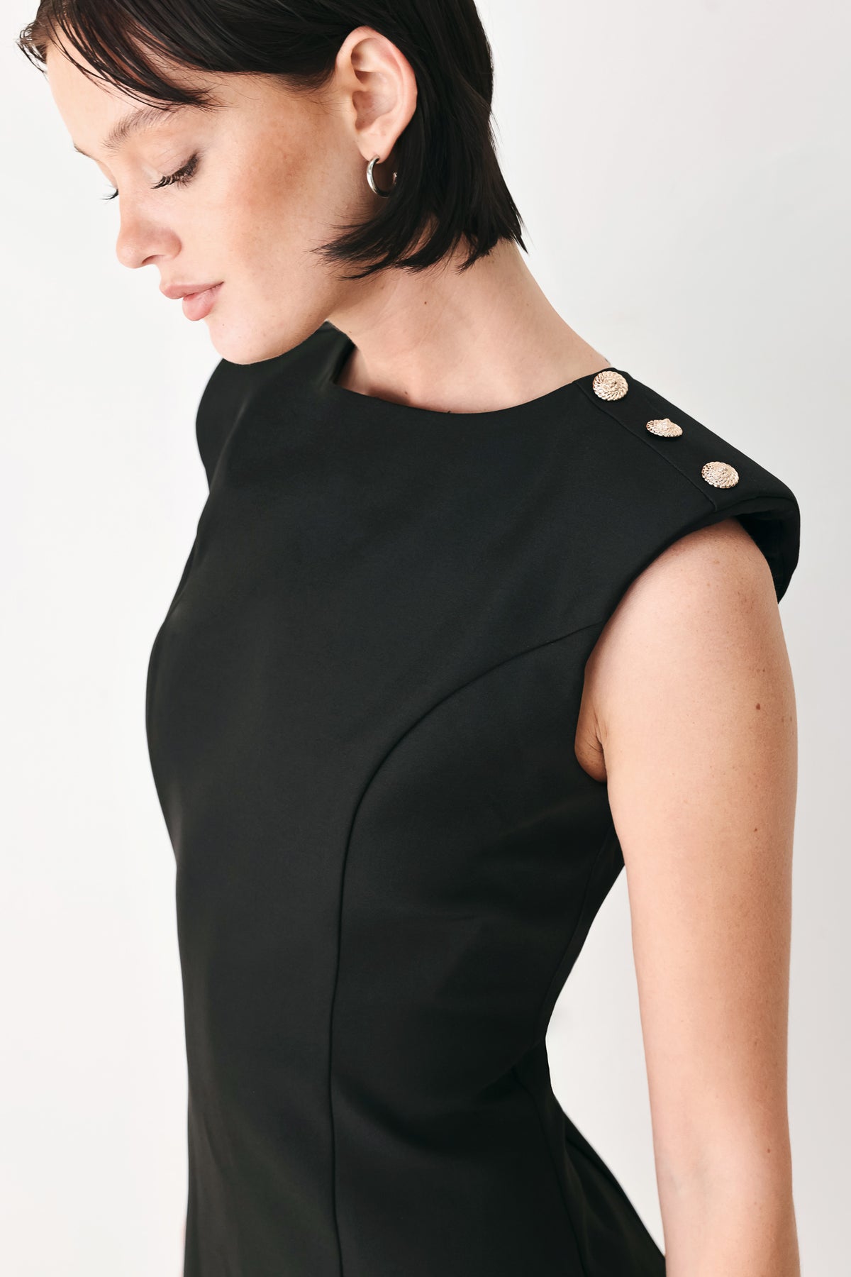 A woman modeling a sleeveless black mini dress with structured shoulders and a boat neckline | FREEMARKET