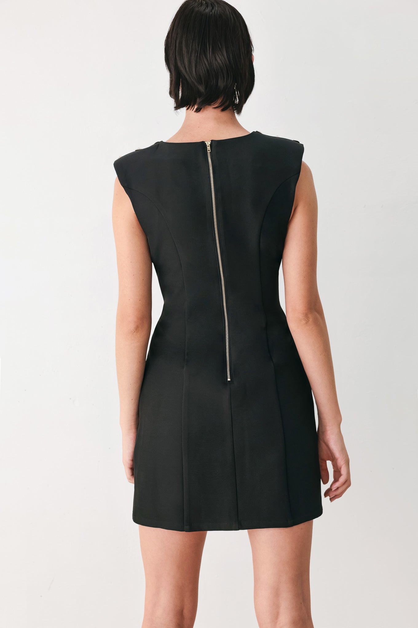 A woman modeling a sleeveless black mini dress with structured shoulders and a boat neckline | FREEMARKET