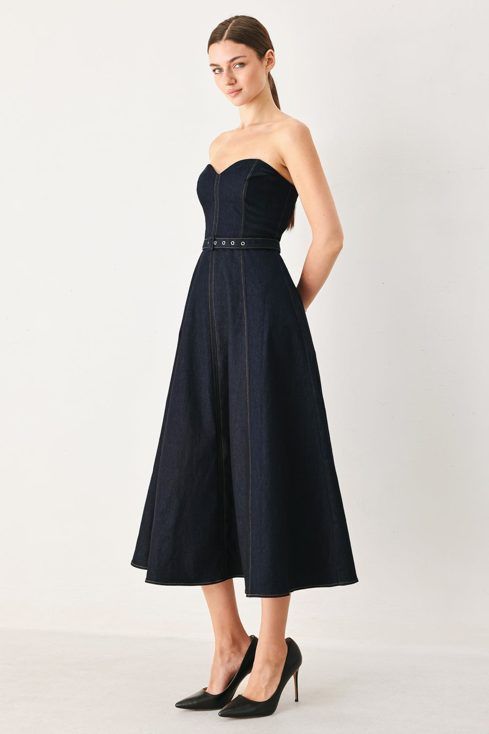 Woman wearing a dark denim strapless midi dress featuring a sweetheart neckline, self belt, circle skirt and back zipper closure | FREEMARKET