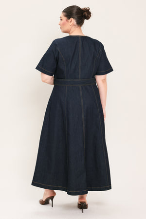 A woman modeling a dark indigo denim midi dress with short sleeves, a button-down front, and a matching belt with a metal buckle | Plus Curve Flying Tomato