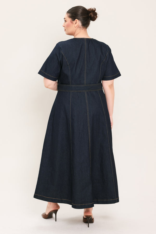 A woman modeling a dark indigo denim midi dress with short sleeves, a button-down front, and a matching belt with a metal buckle | Plus Curve Flying Tomato