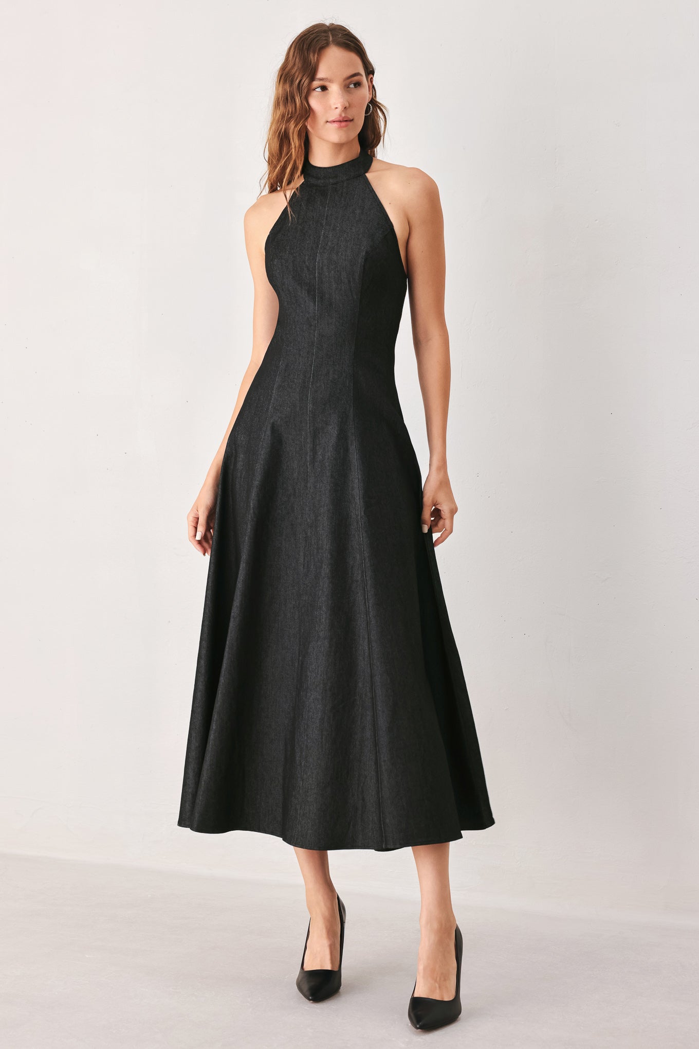 A woman modeling a sleeveless black midi dress with a high mock neck and flared skirt | FREEMARKET