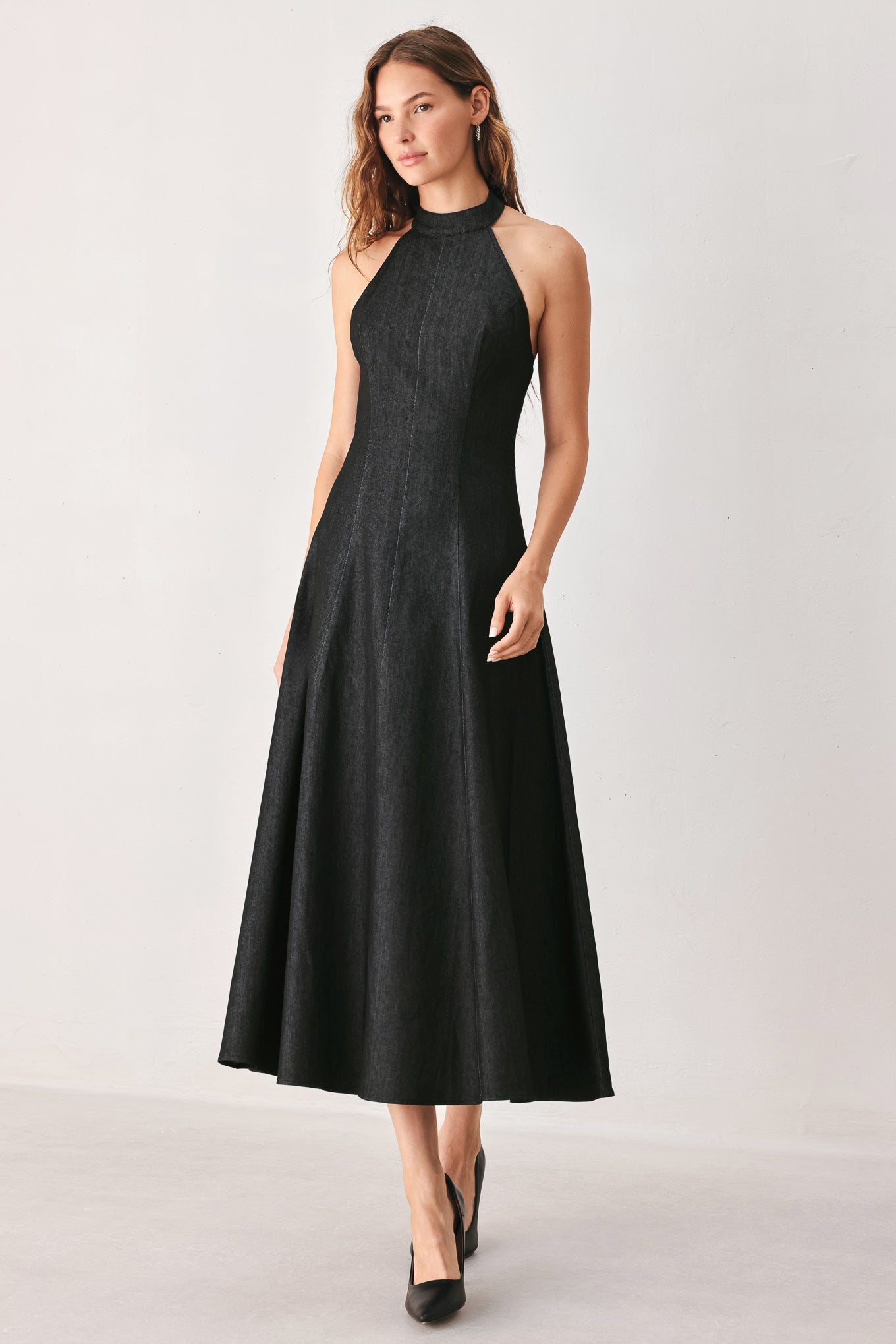 A woman modeling a sleeveless black midi dress with a high mock neck and flared skirt | FREEMARKET