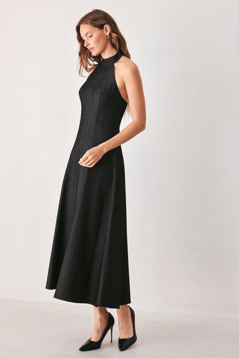 A woman modeling a sleeveless black midi dress with a high mock neck and flared skirt | FREEMARKET