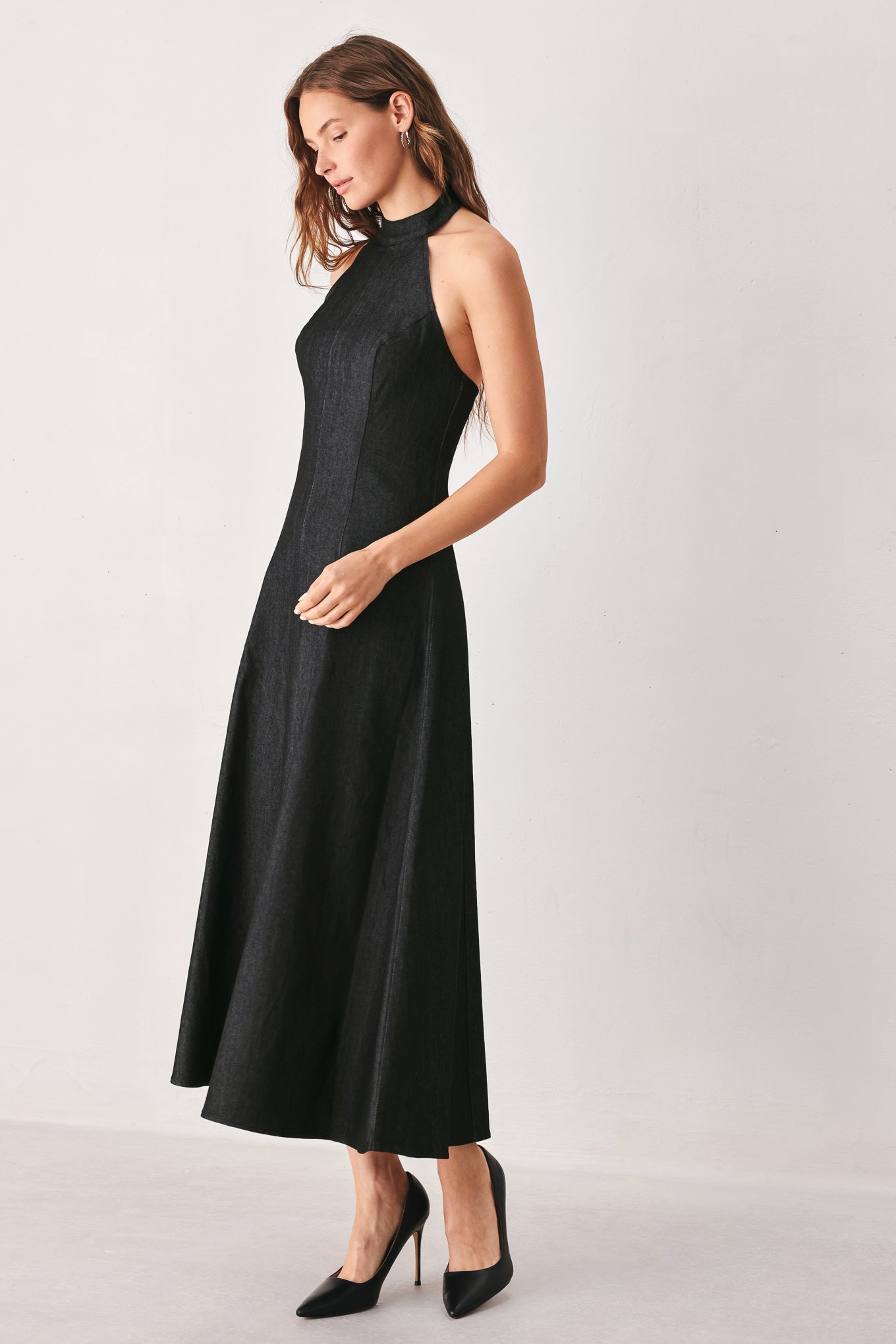 A woman modeling a sleeveless black midi dress with a high mock neck and flared skirt | FREEMARKET
