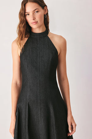 A woman modeling a sleeveless black midi dress with a high mock neck and flared skirt | FREEMARKET